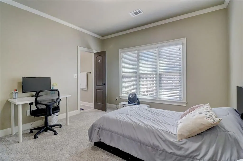 Carpeted bedroom featuring multiple windows and ornamental molding