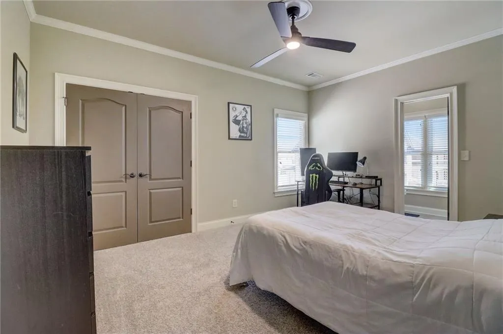 Bedroom with ceiling fan, a closet, carpet flooring, and ornamental molding