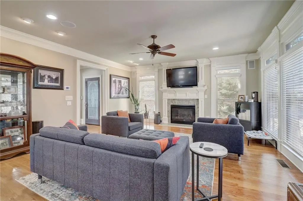Living room with a wealth of natural light, ornamental molding, ceiling fan, and light wood-type flooring