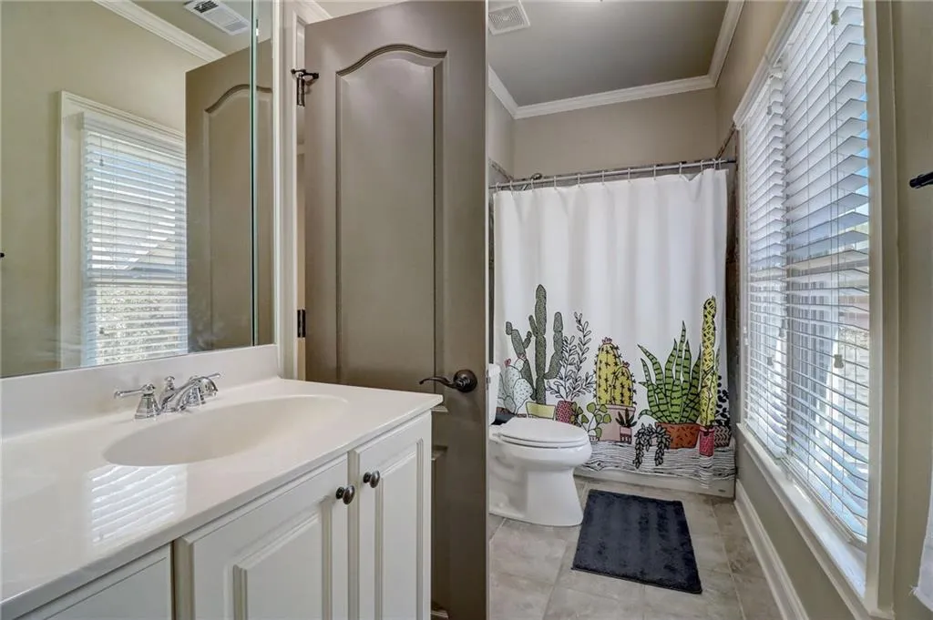 Bathroom featuring tile flooring, oversized vanity, toilet, and ornamental molding