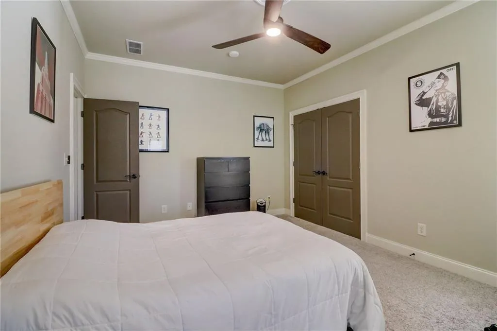 Carpeted bedroom with a closet, ceiling fan, and ornamental molding