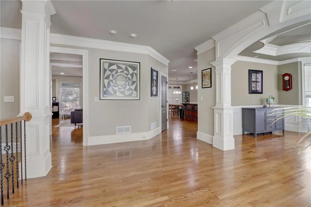 Foyer featuring decorative columns, light wood-type flooring, and crown molding
