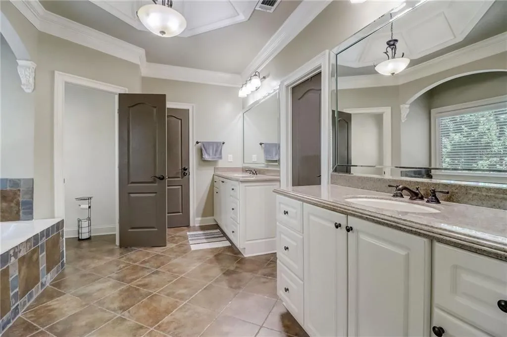 Bathroom featuring tile floors, dual bowl vanity, a washtub, and ornamental molding