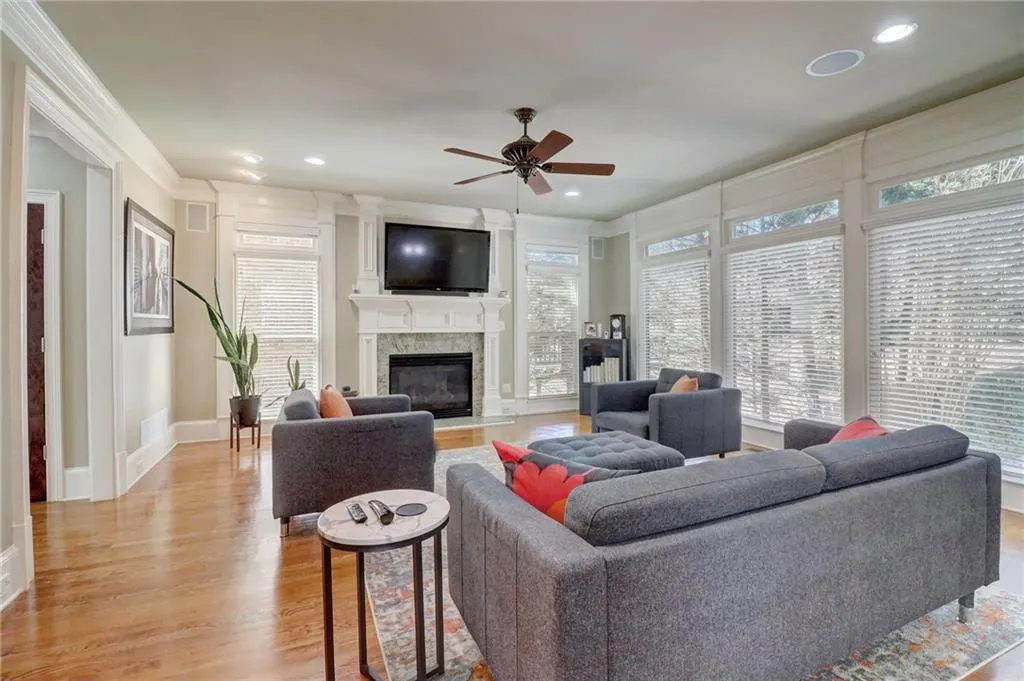 Living room featuring crown molding, ceiling fan, a high end fireplace, and light hardwood / wood-style flooring