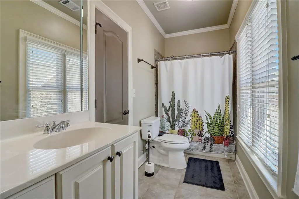 Bathroom with tile floors, ornamental molding, toilet, and oversized vanity