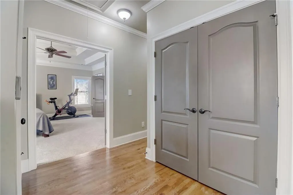 Hall featuring ornamental molding, a raised ceiling, and light colored carpet