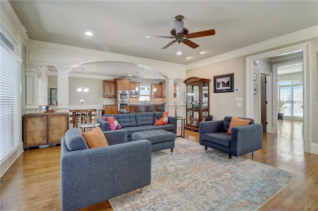 Living room with crown molding, ceiling fan, ornate columns, and light hardwood / wood-style flooring