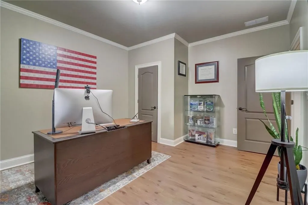 Home office with light hardwood / wood-style flooring and crown molding
