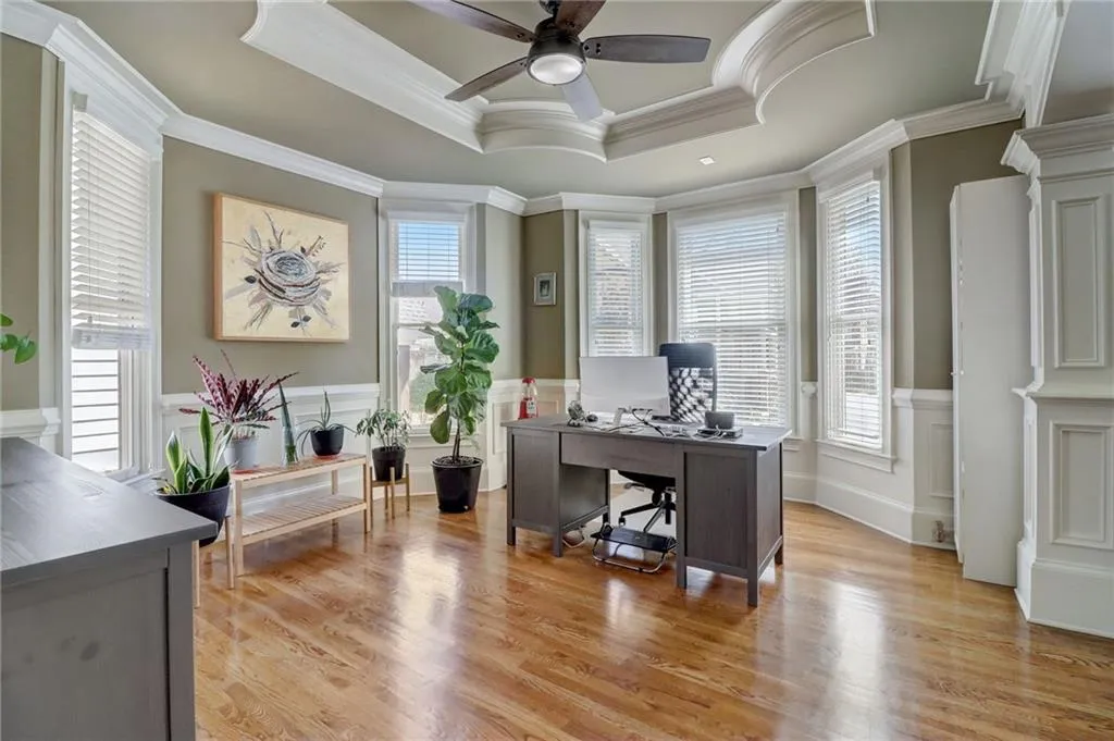 Home office featuring a tray ceiling, plenty of natural light, and light wood-type flooring