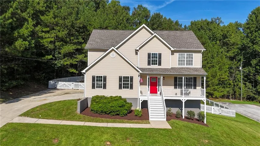 Two-story residence featuring light-colored siding, a covered front porch, and a bright red entry door