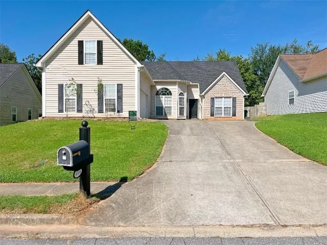 Two-story residence with light-colored siding, a dark shingle roof, a two-car garage, and a concrete driveway