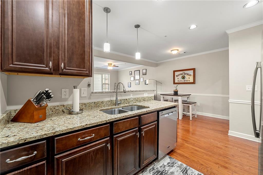 Kitchen featuring decorative light fixtures, dishwasher, light hardwood / wood-style floors, ceiling fan, and sink