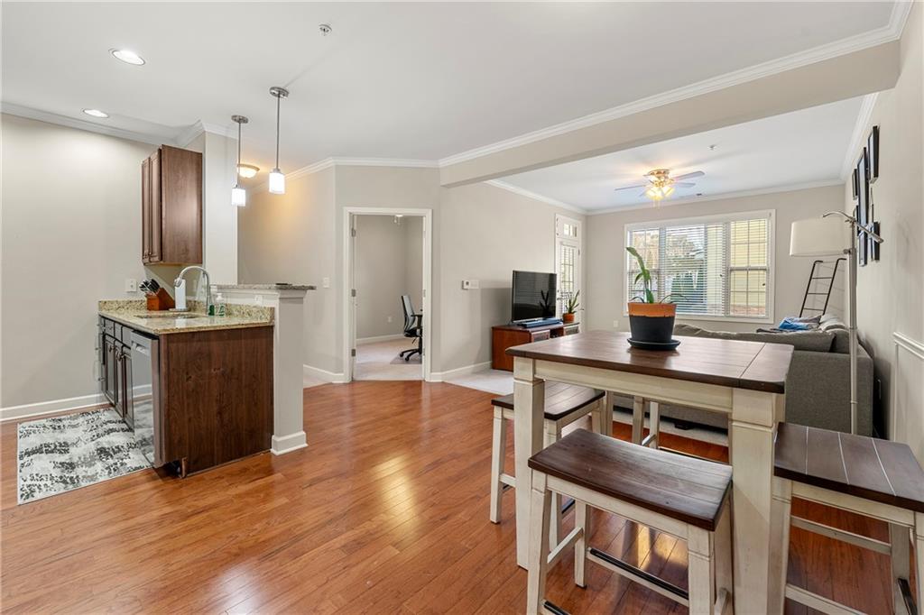 Dining area with light hardwood / wood-style flooring, ornamental molding, sink, and ceiling fan