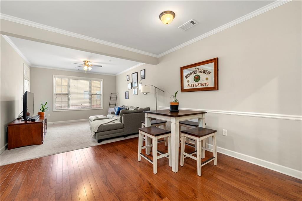 Dining room with dark hardwood / wood-style floors, ornamental molding, and ceiling fan