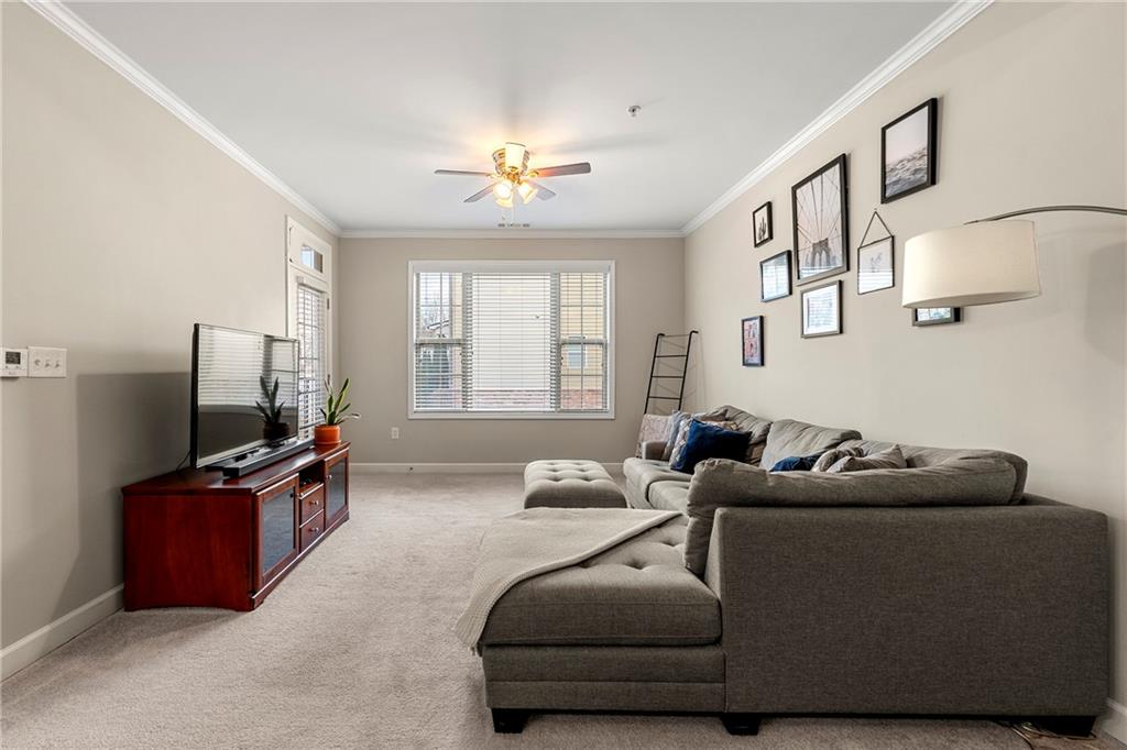 Living room featuring crown molding, light colored carpet, and ceiling fan