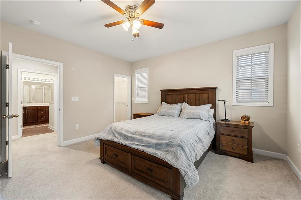 Bedroom with ensuite bath, light carpet, and ceiling fan