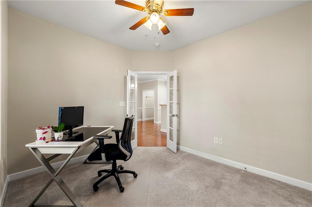 Office area with french doors, light carpet, and ceiling fan