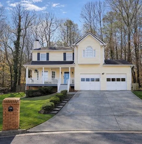 Traditional two-story residence featuring light-colored siding, a covered front porch, and a light blue entry door