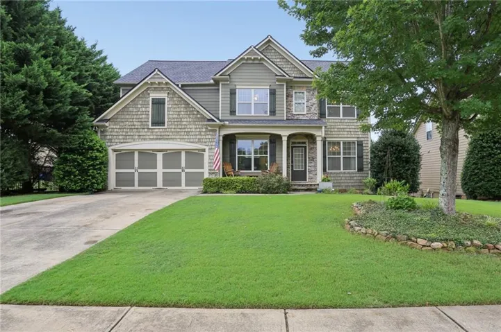Classic Colonial-style residence featuring a steeply pitched roofline with multiple gables, composite shingle roofing, and brick and stone exterior cladding
