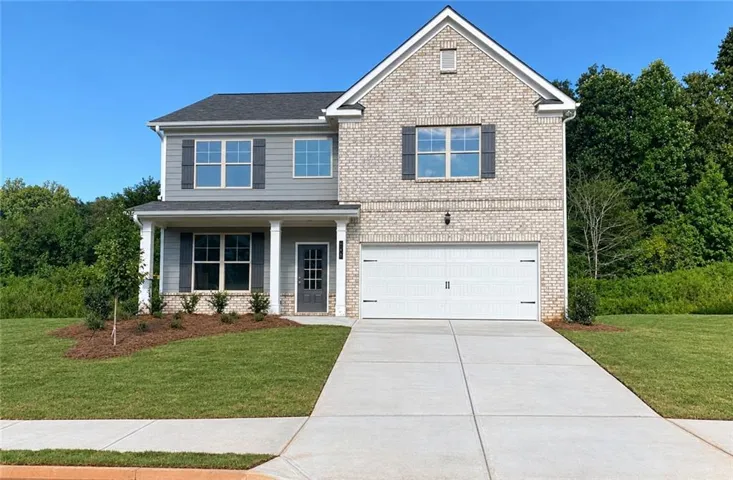 Two-story residence featuring a brick and siding exterior, a two-car garage, covered entry porch with columns, and a concrete driveway