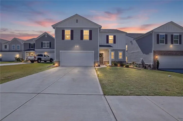 Siding exterior with accent shutters, attached two-car garage, concrete driveway, and front lawn with landscape lighting