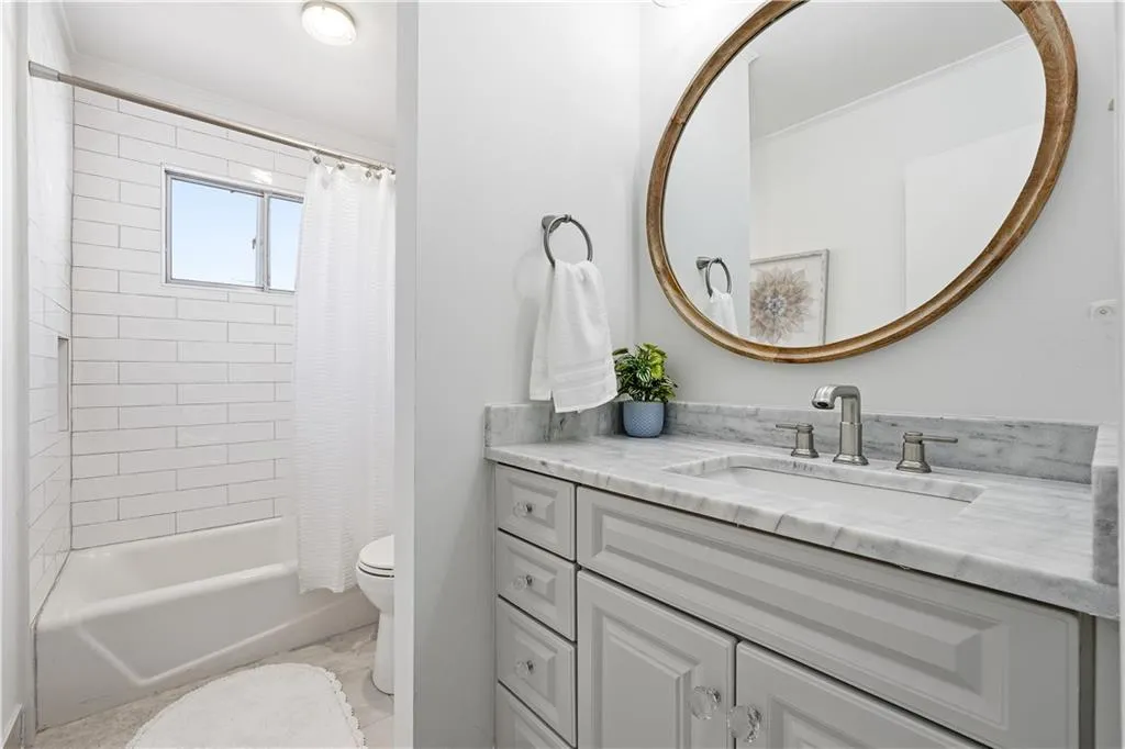 Secondary bath with updated vanity, marble counters and tile bath.