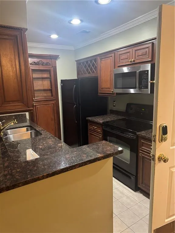 Kitchen with crown molding, black appliances, light tile patterned floors, dark stone counters, and recessed lighting
