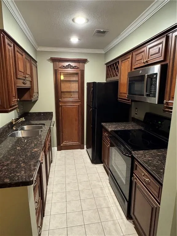 Kitchen featuring stainless steel range, crown molding, black microwave, a textured ceiling, and light tile patterned flooring