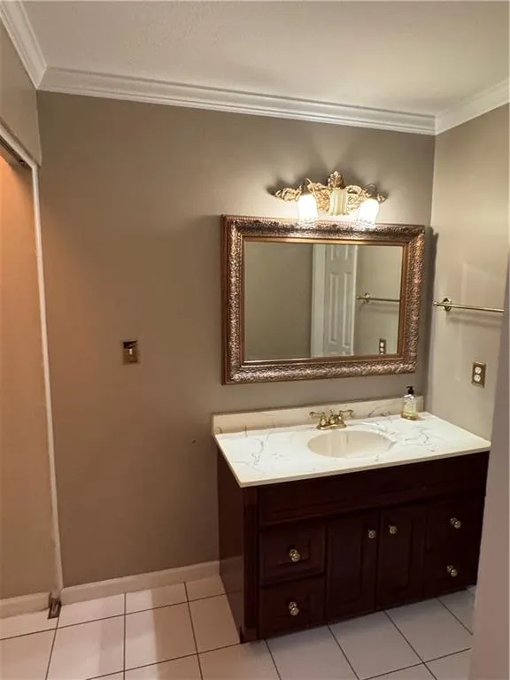Bathroom featuring crown molding, light tile patterned floors, and vanity