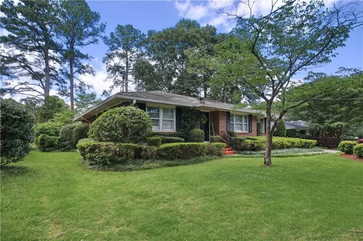 Brick exterior residence with a gabled roof, featuring dark shutters and white-framed windows