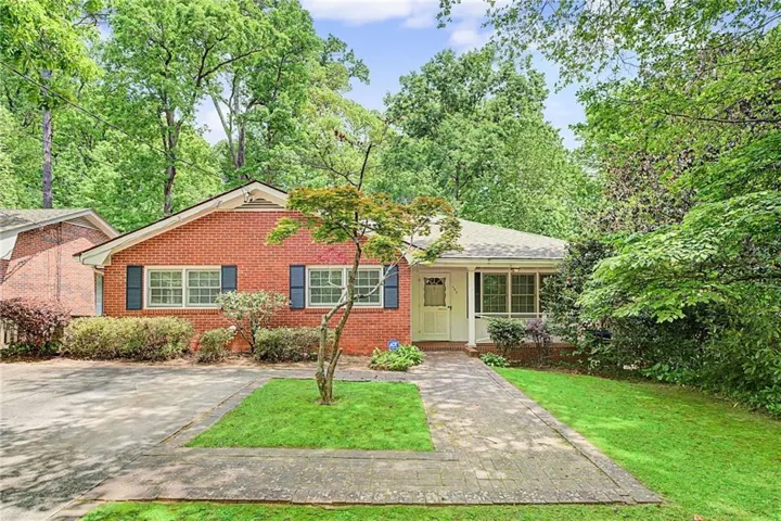 Brick exterior with dark shutters, covered front entry, and a paved walkway