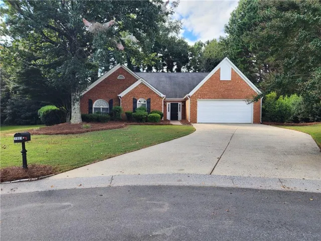 Brick exterior with white trim, arched window accents, attached garage, and a concrete driveway