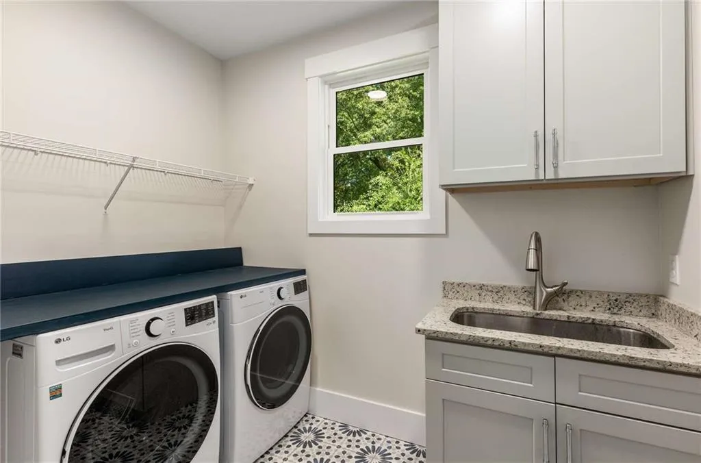 Laundry area with washer and clothes dryer, tile patterned floors, and cabinet space