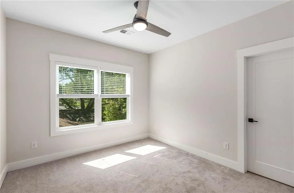 Carpeted empty room with baseboards and a ceiling fan