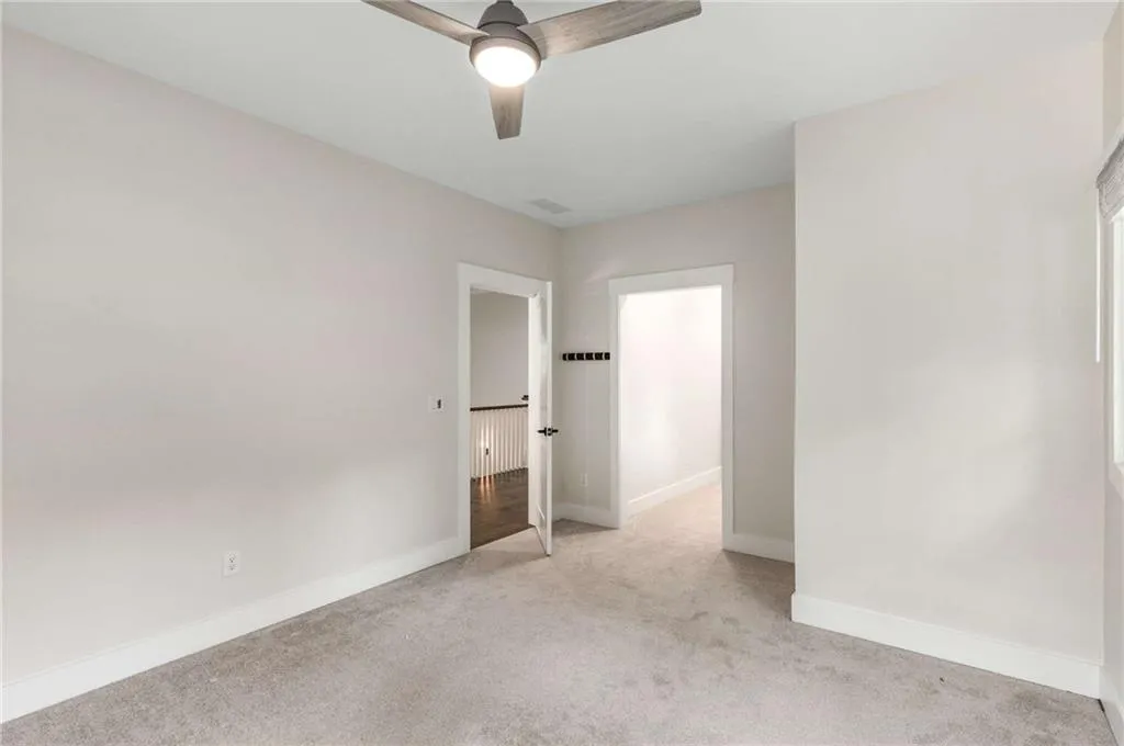 Unfurnished bedroom with light colored carpet and ceiling fan