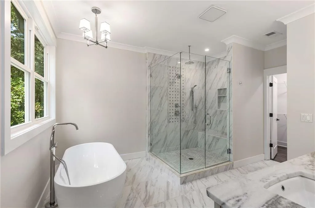 Full bathroom with crown molding, a freestanding bath, a marble finish shower, vanity, and marble finish floors