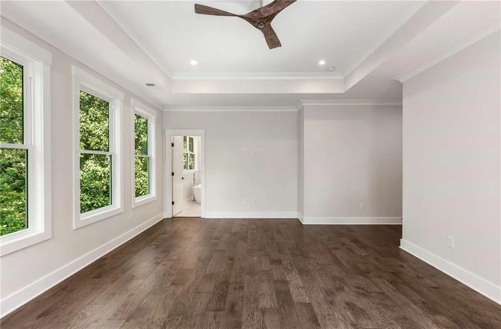 Spare room with a raised ceiling, dark wood-style flooring, recessed lighting, a ceiling fan, and ornamental molding