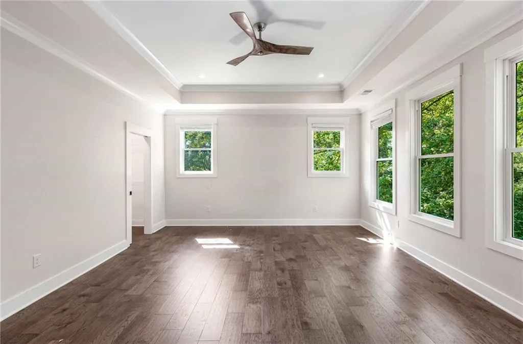 Spare room featuring dark wood-type flooring, a tray ceiling, ceiling fan, recessed lighting, and ornamental molding