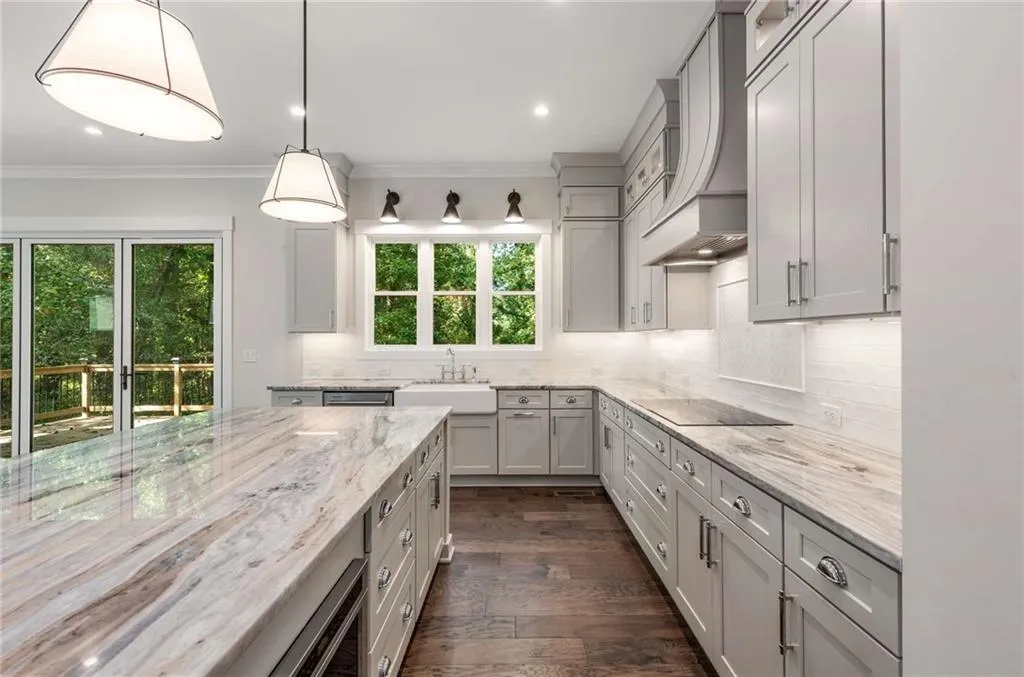Kitchen featuring pendant lighting, backsplash, dark wood-style flooring, light stone countertops, and custom exhaust hood
