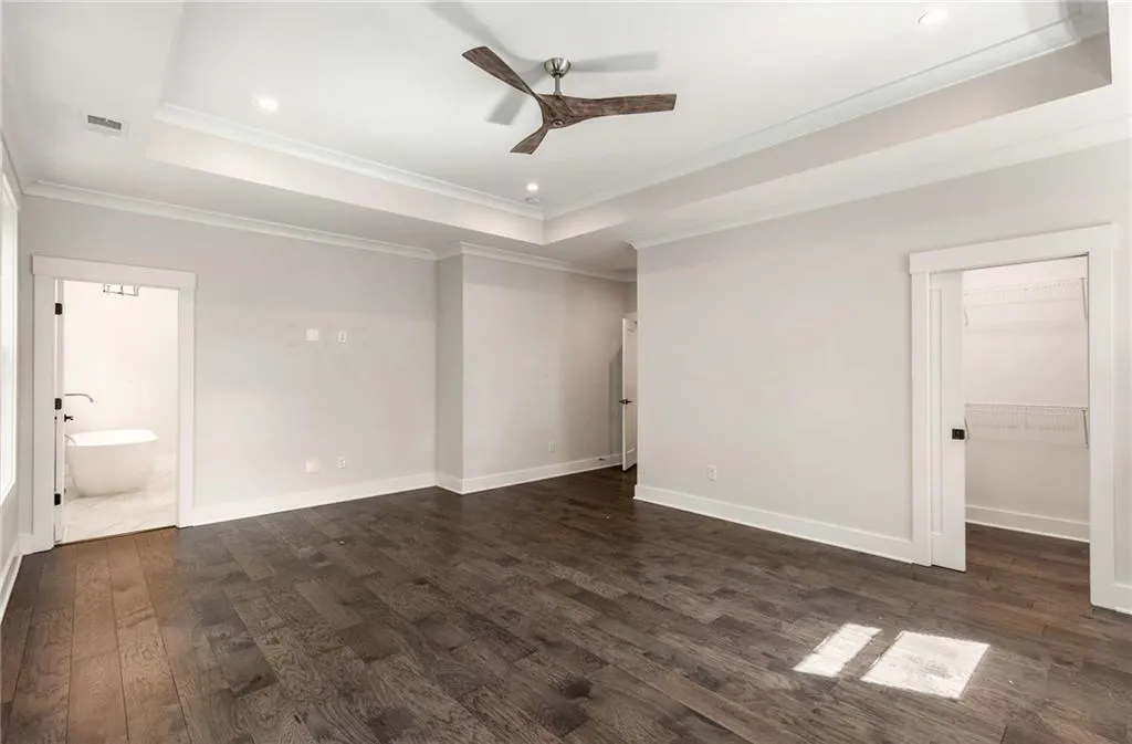 Unfurnished bedroom with a raised ceiling, crown molding, dark wood-type flooring, ceiling fan, and recessed lighting