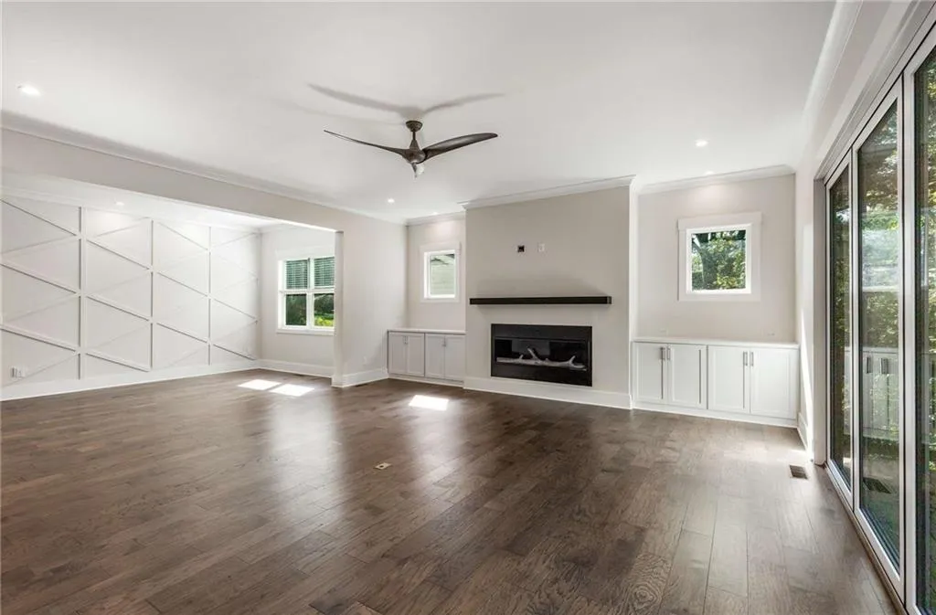 Unfurnished living room with a glass covered fireplace, a ceiling fan, ornamental molding, dark wood-style floors, and recessed lighting