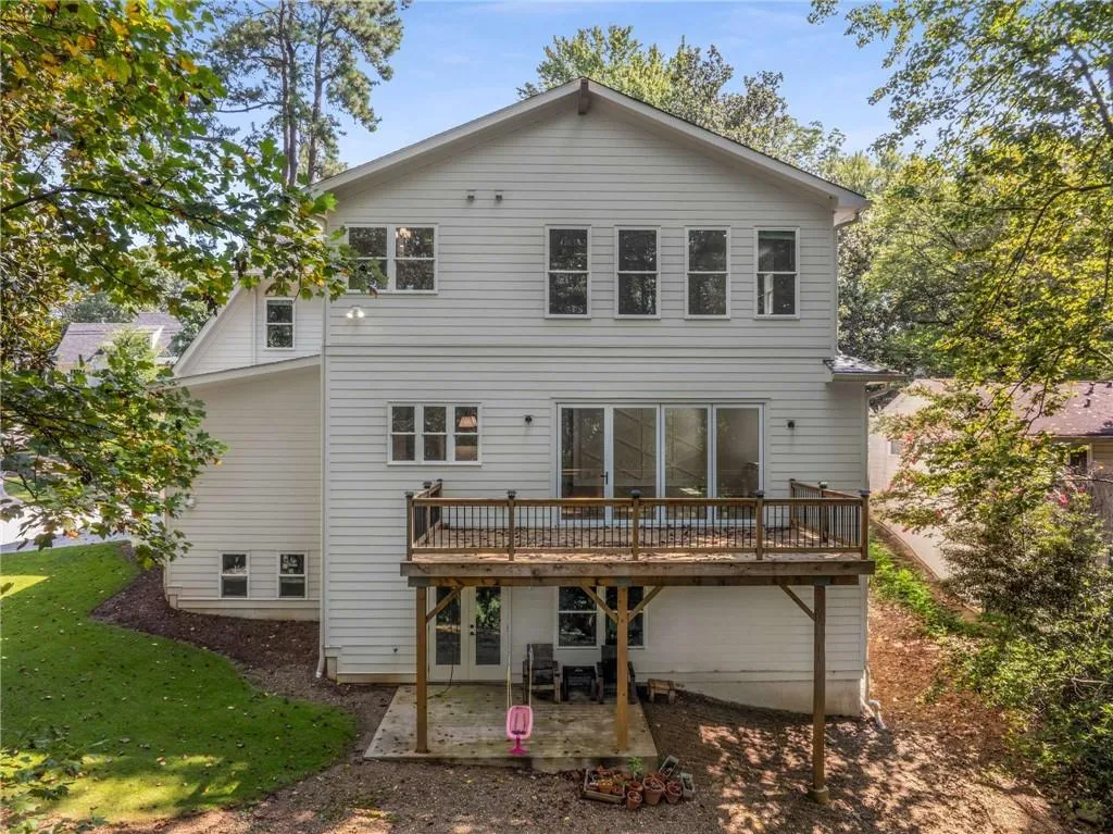 Back of house with a wooden deck, a patio, and a yard