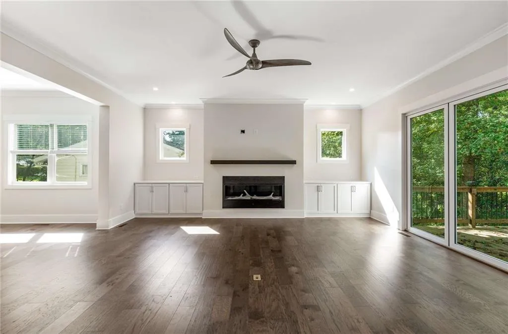 Unfurnished living room featuring crown molding, dark wood-style floors, a ceiling fan, a glass covered fireplace, and recessed lighting