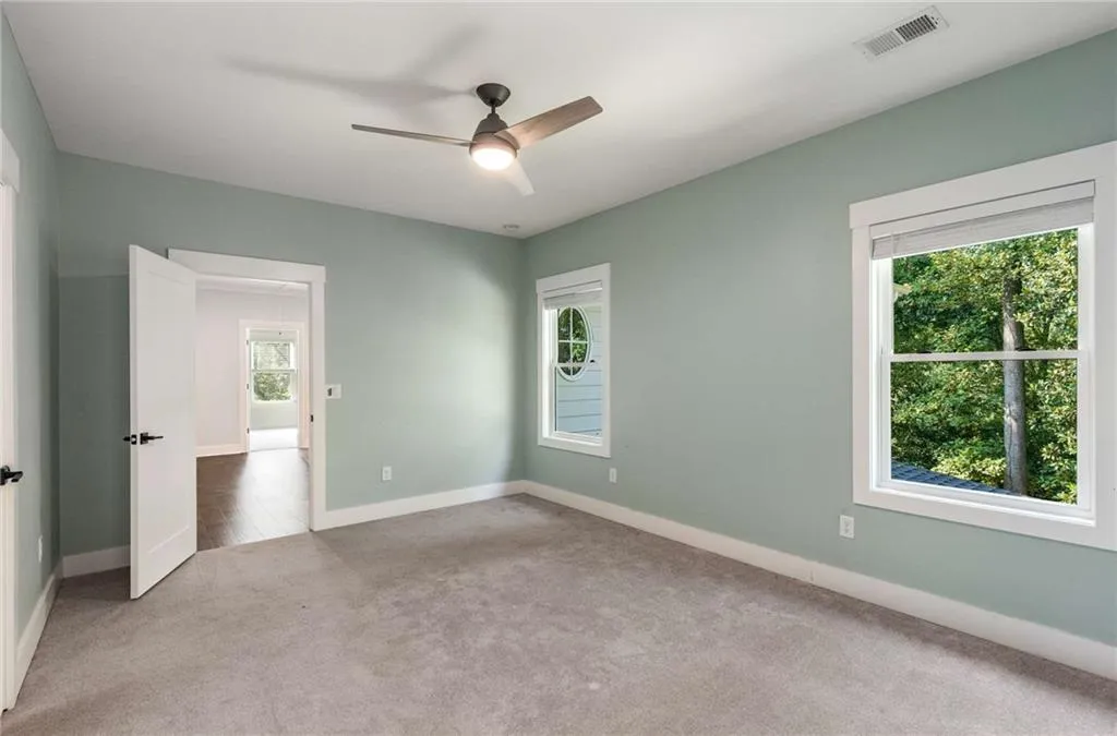 Empty room featuring carpet floors, healthy amount of natural light, and a ceiling fan