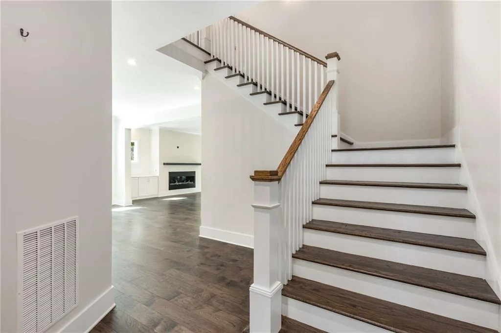 Staircase featuring wood finished floors, a fireplace, and recessed lighting