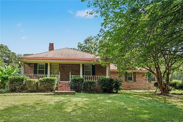 Brick exterior residence with a metal roof and a covered front porch featuring white railing