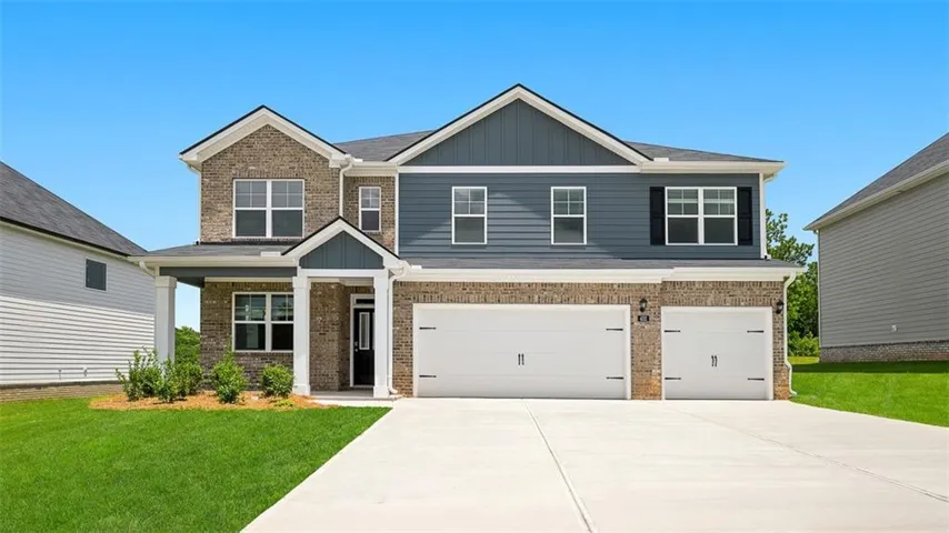Two-story residence featuring a brick and siding exterior with a contrasting blue accent, a three-car garage with white doors, a covered entry with white columns, a dark front door, and a concrete driveway
