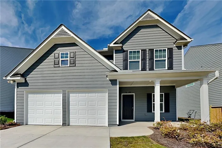 Two-story exterior with gray siding, a covered entry, two-car garage, and established landscaping