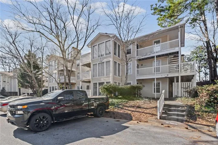 Multi-level residential building featuring exterior siding, private balconies, and concrete steps with white railings