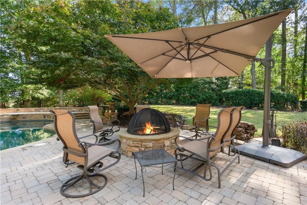 Built in Firepit on Extended Paved Patio sits poolside and adjacent to large level grassy backyard.